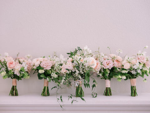 Five lush and ivory floral bouquets lined up on on their stems on a ledge.